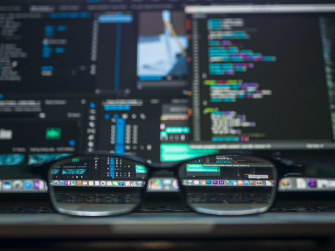 pair of glasses in front of computer screen with code